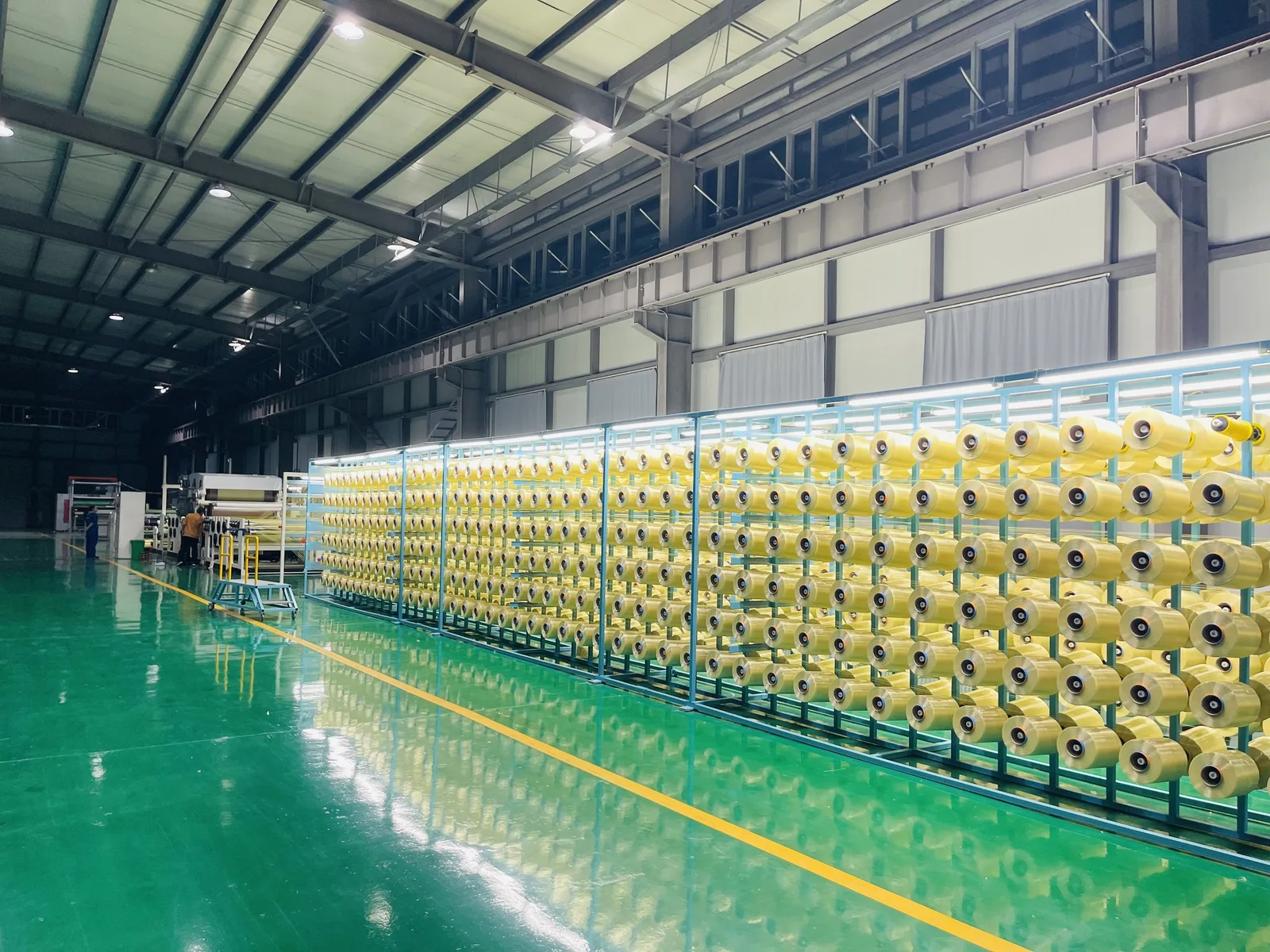 Para-aramid creel room with rows of yellow yarn packages