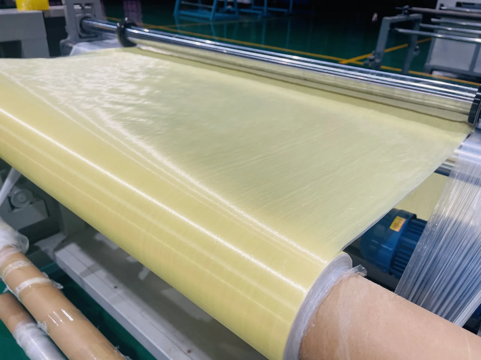 Para-aramid UD fabric coming off the forming line, yellow sheet on a steel roller